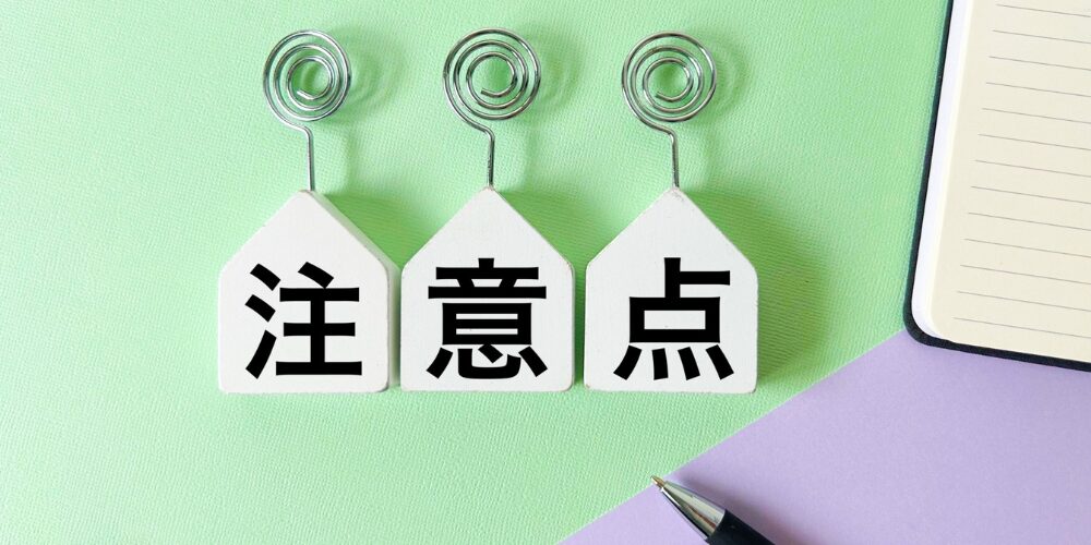 パステルカラーの背景に、ハウス型の木製クリップホルダー３つにそれぞれ「注」「意」「点」と黒字で書かれ、横にペンとノートが配置された写真。
