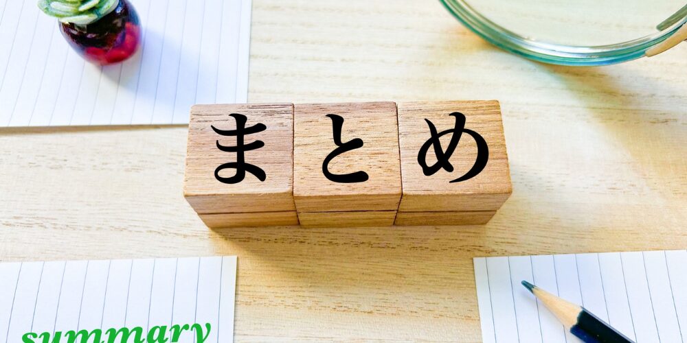 木の机の上に「まとめ」と書かれたブロックと、メモや鉛筆、観葉植物などが添えられたイメージ写真