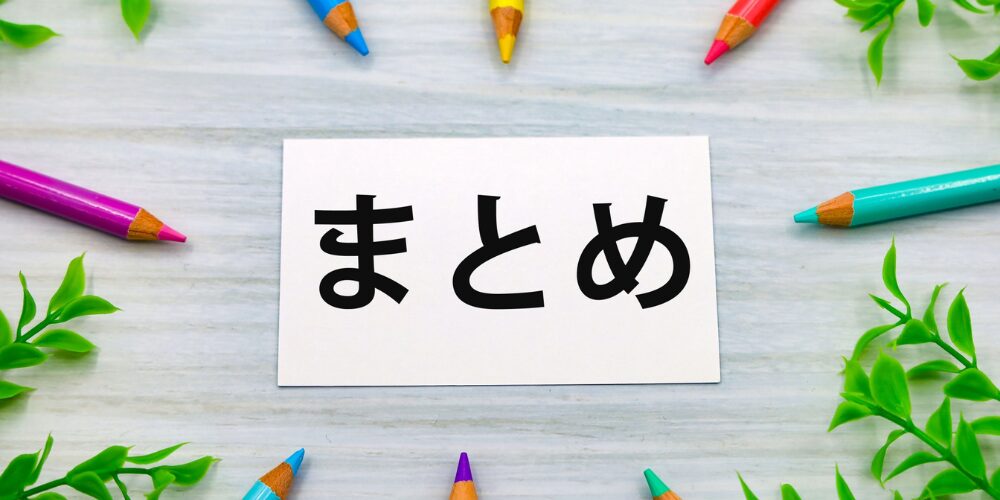 淡い木目のテーブル上に白いカードが置かれ、黒文字で『まとめ』と書かれ、周囲にカラフルな色鉛筆と観葉植物が配されたイメージ