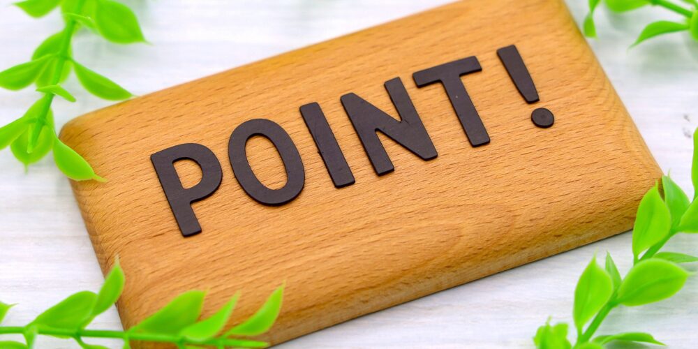 木製の板に黒文字で『POINT!』と書かれ、周囲に緑の観葉植物の葉があしらわれたイメージ